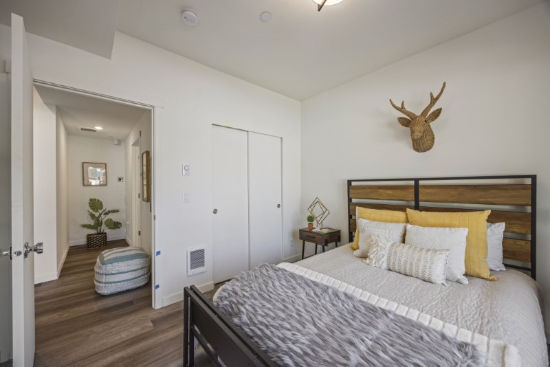Bedroom with dark wood-look plank flooring and an open doorway to a hallway finished in the same flooring.