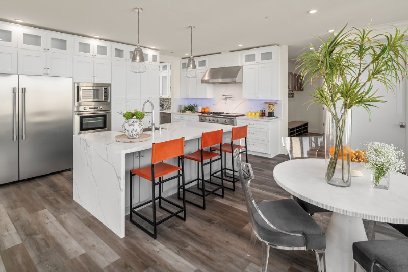 Kitchen with an island, cabinetry, and appliances set on light wood-look plank flooring.