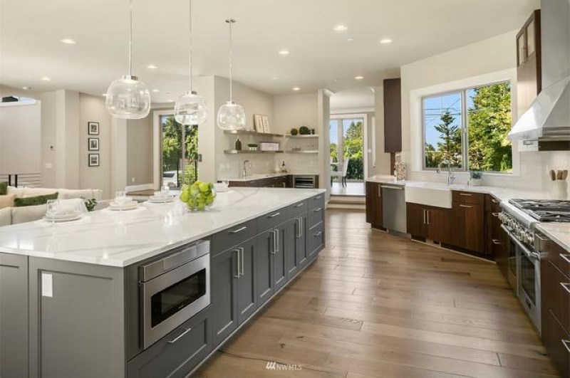 Modern kitchen with a large gray island, white countertops, and light brown luxury vinyl plank flooring.