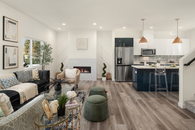 Living room flowing into a kitchen with the same wood-look plank flooring carried across both spaces.