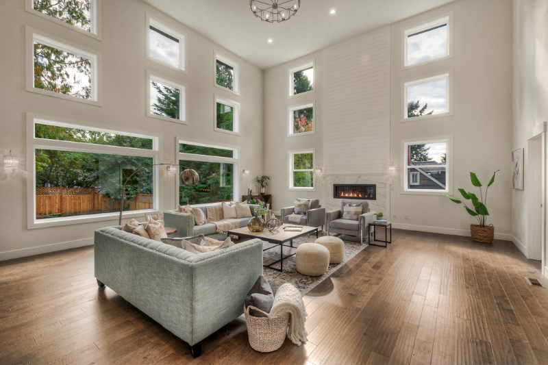 Spacious, well-lit modern living room featuring high ceilings, large windows, and brown LVP flooring throughout
